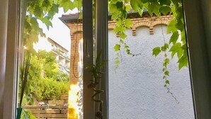 A view through a window with a white wall and a brick building in the background.