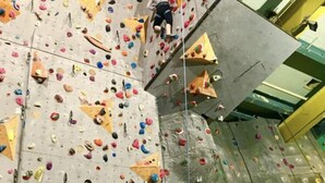 A climbing wall with various holds and a climber in mid-action.