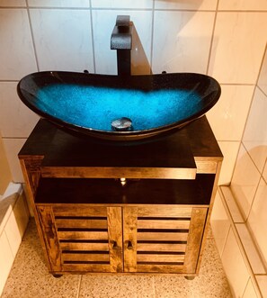 A black sink with a blue interior on a wooden cabinet with a black top.