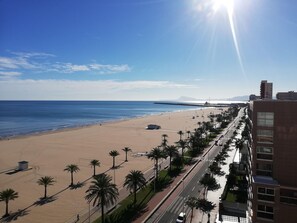 A beach with palm trees and a road alongside a building. - Infante E3-9 Solo Familias! (Playa de Gandía)