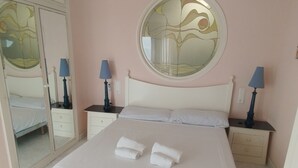 Een slaapkamer met een bed, twee nachtkastjes, een spiegel en een kledingkast.