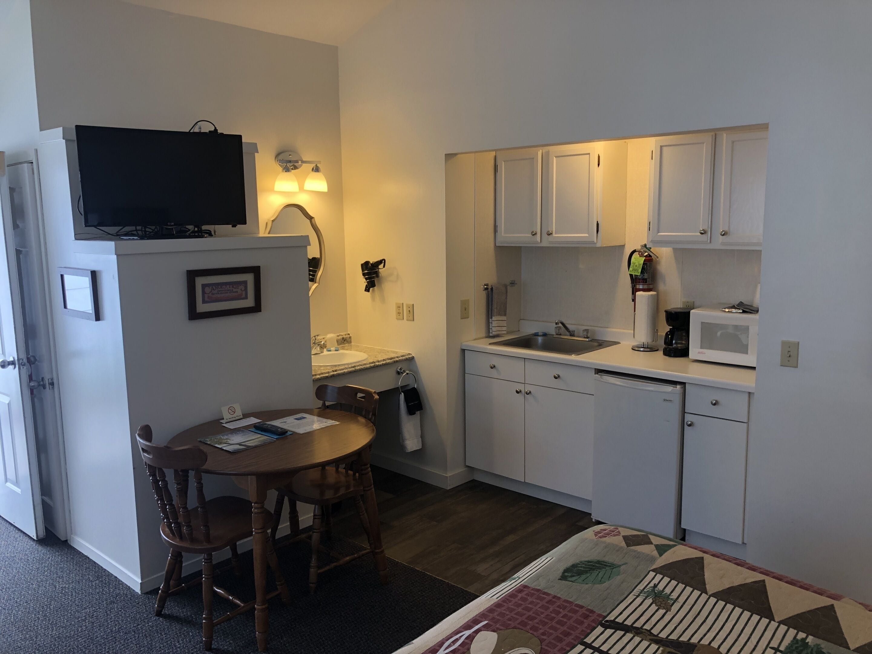 A compact kitchen with white cabinets, a microwave, a sink, and a dining area with a table and chairs.