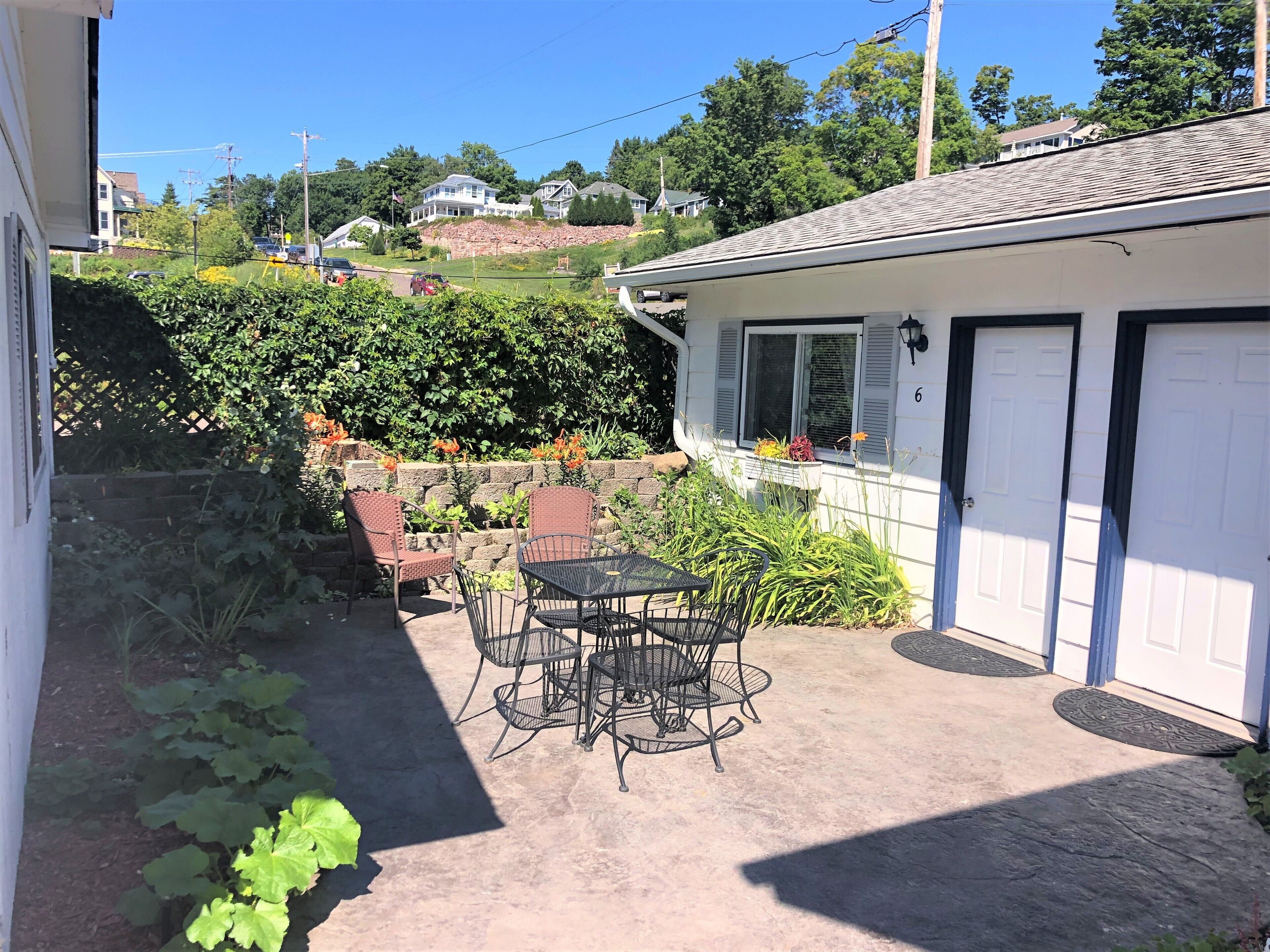 A patio with outdoor furniture, a stone wall, and a view of a residential area.