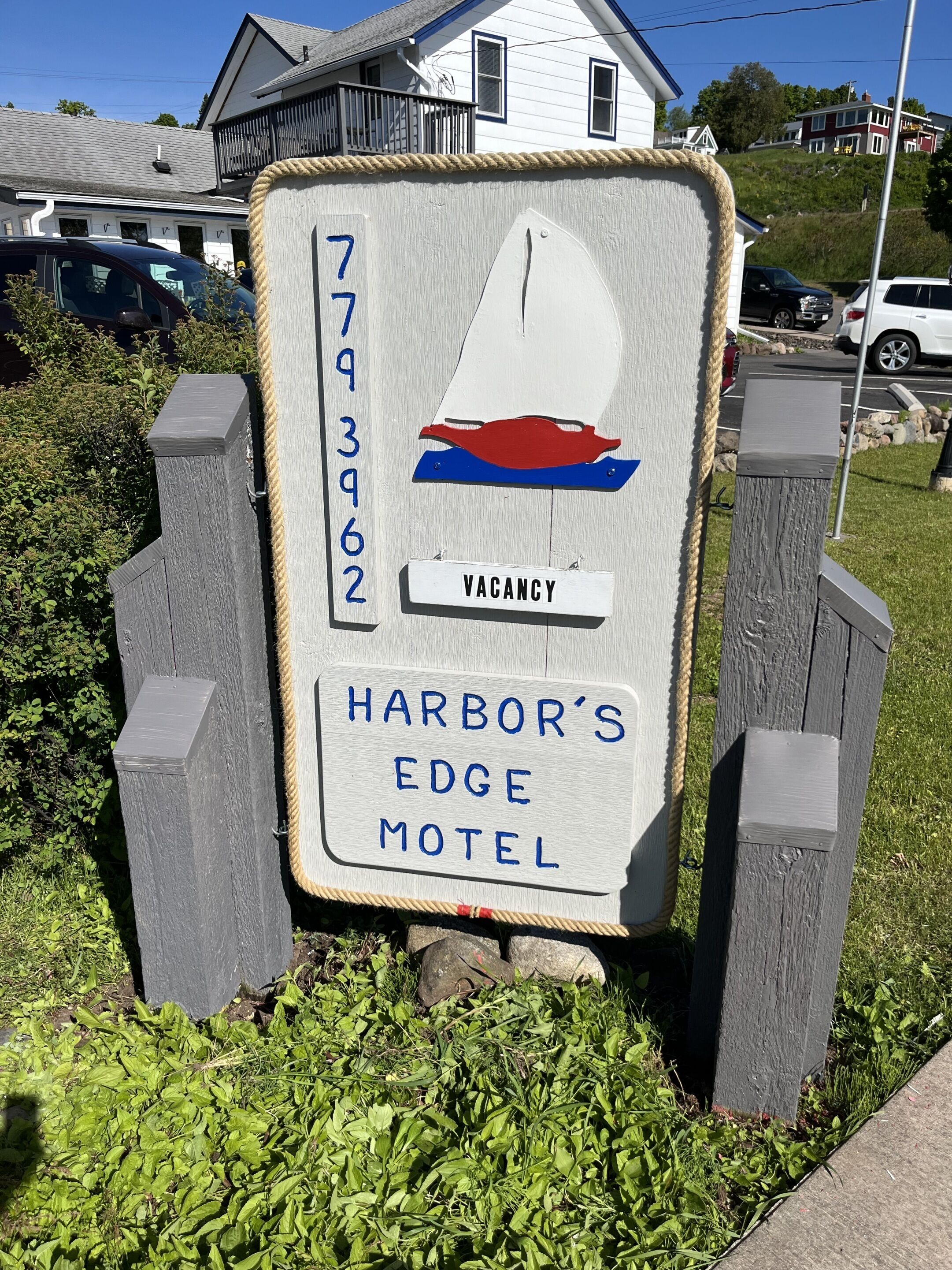 A wooden signboard for Harbor's Edge Motel with a 'VACANCY' label and a sailboat graphic.