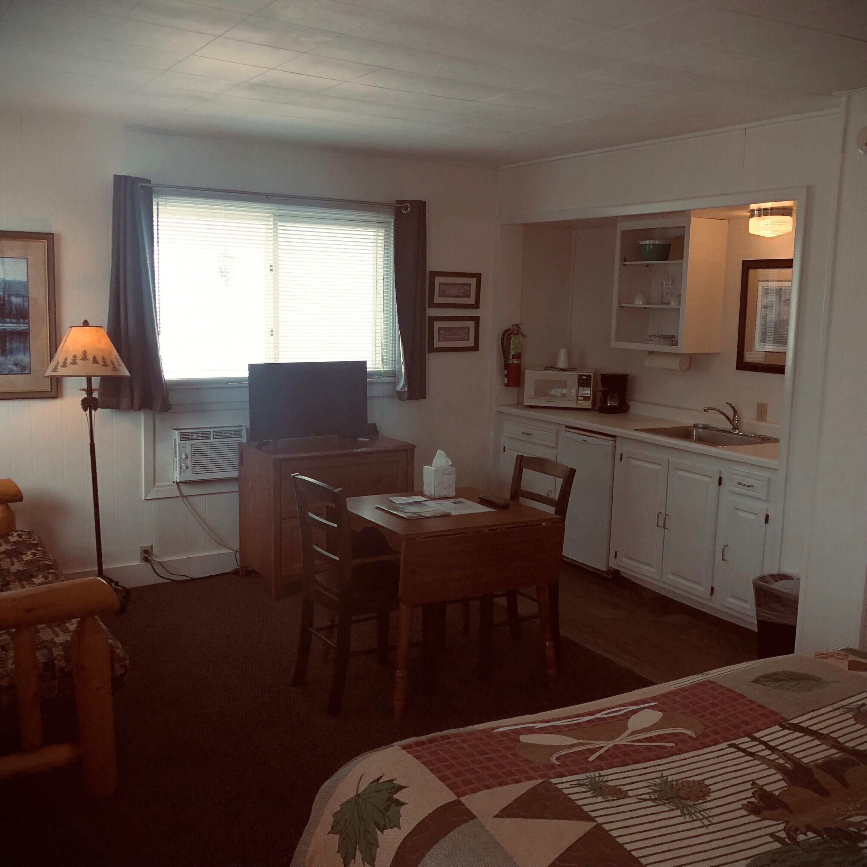 Une chambre d’hôtel compacte comprenant un coin cuisine, un espace repas et un lit.