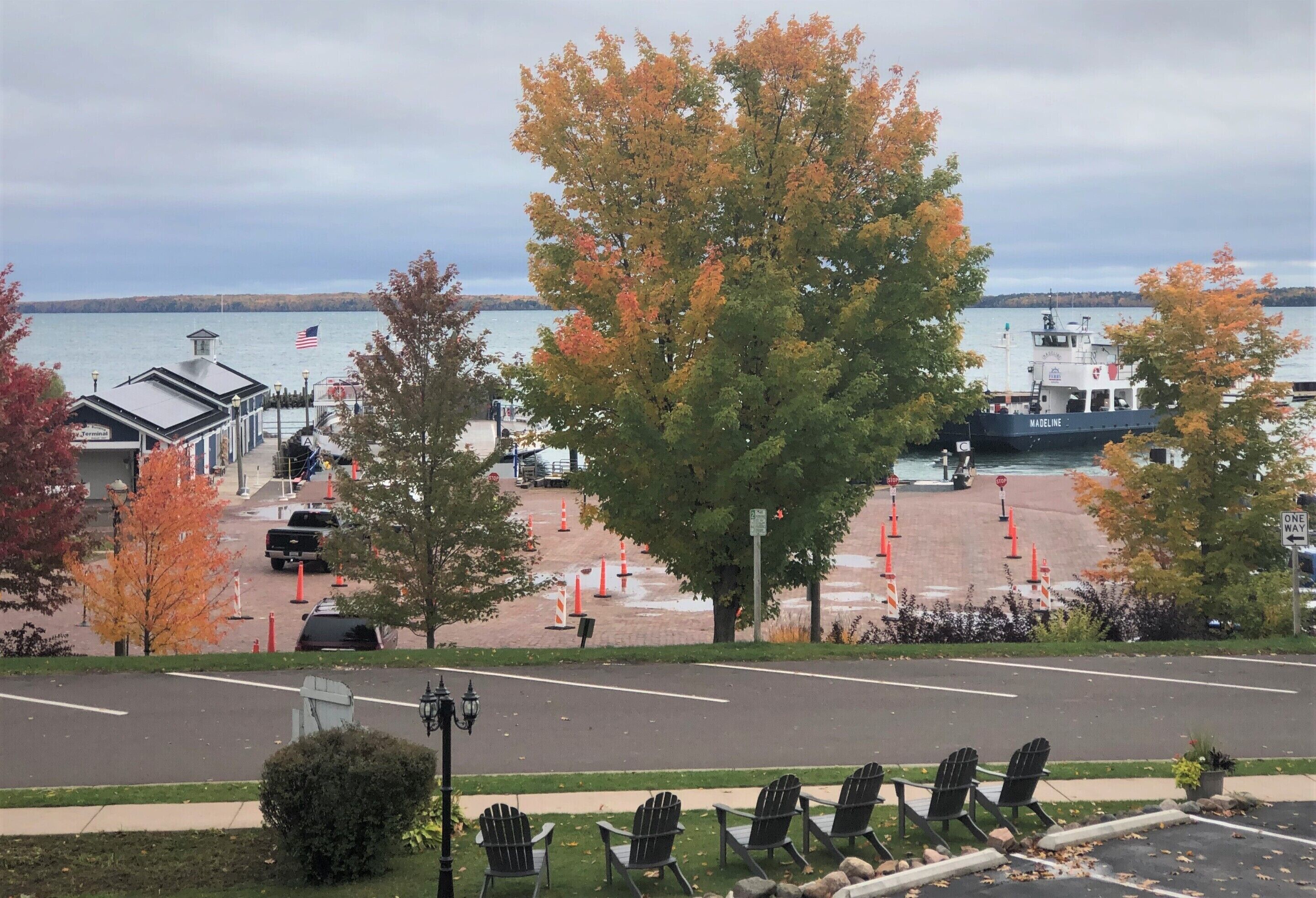 A waterfront view with a dock, a boat named 'WAGELINE', and a row of black chairs in the foreground.