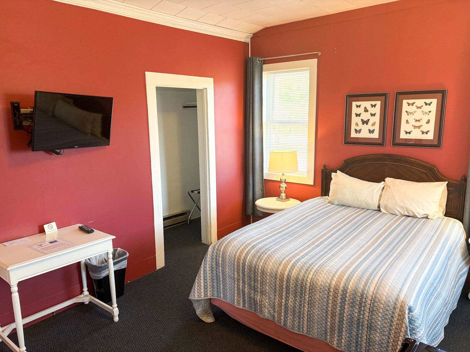 Une chambre d’hôtel avec un lit, un bureau, une télévision et des tableaux représentant des papillons accrochés au mur.