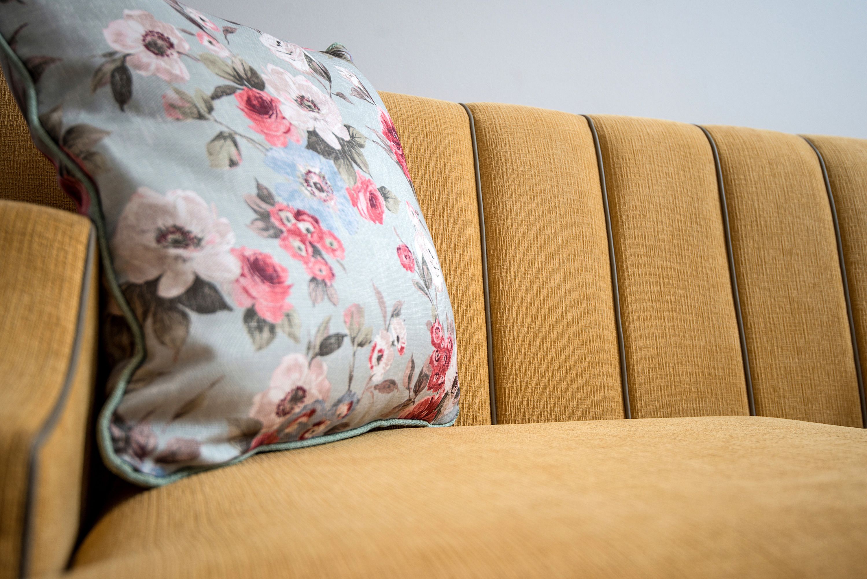 Un sofá con un cojín floral y otra almohada texturizada.
