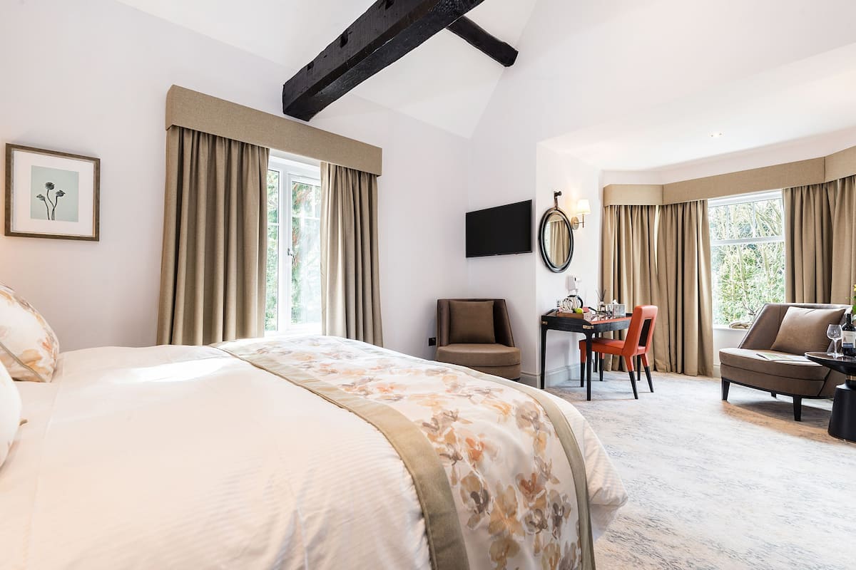 A hotel room with a large bed, a desk with a chair, a sofa, and a TV mounted on the wall.