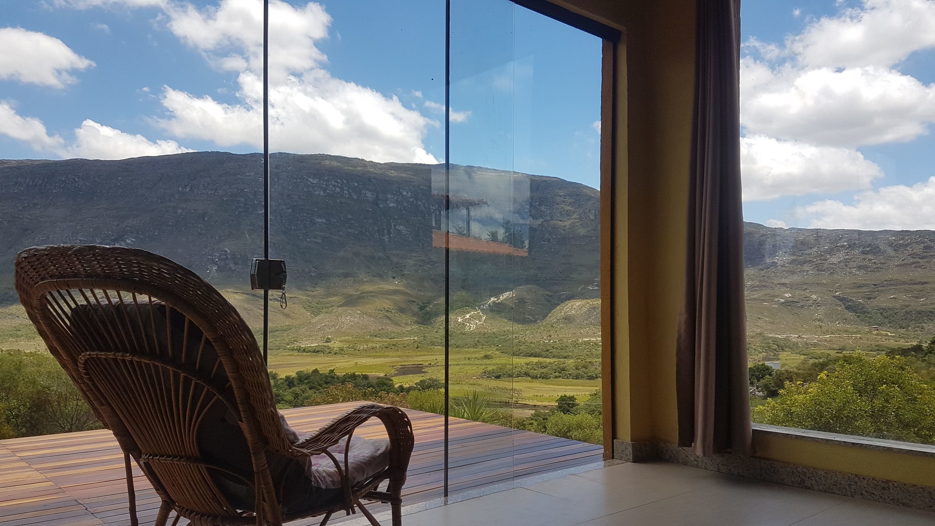 A wicker chair on a balcony overlooking a mountainous landscape.