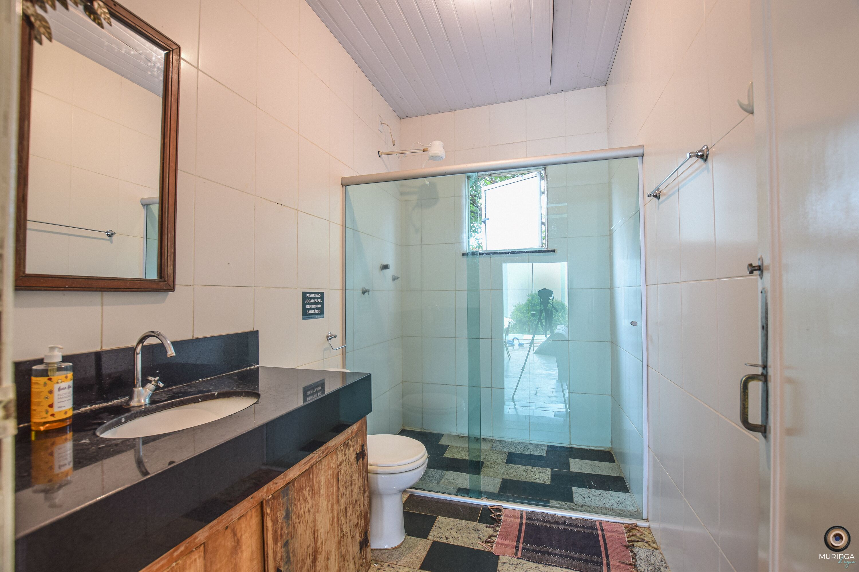Ein Badezimmer mit Duschkabine aus Glas, einem Holzkosmetikschrank und einer weißen Toilette.