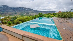 Una piscina con cubierta de madera, rodeada de vegetación y con vistas a un paisaje montañoso.