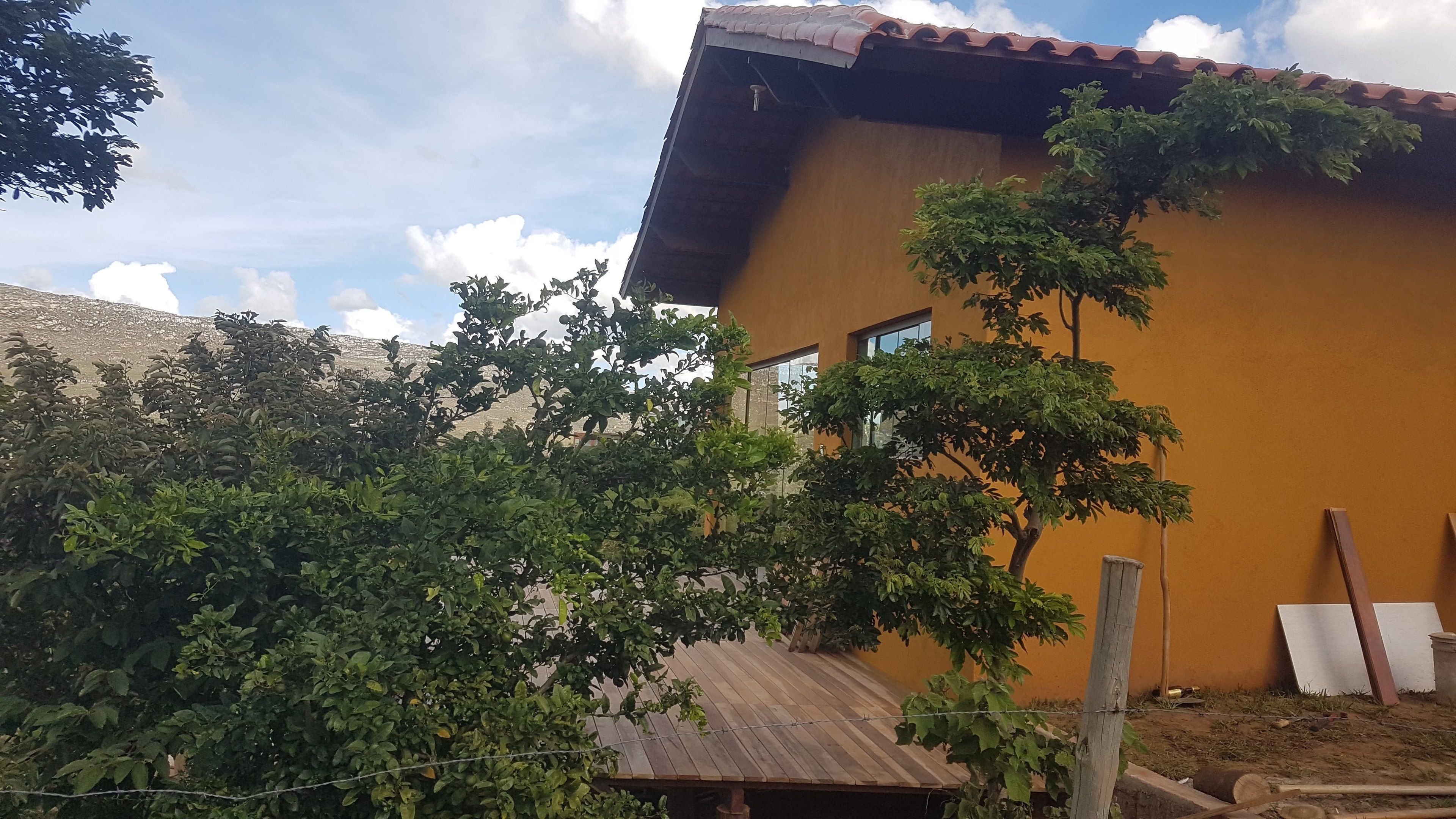 Una casa con fachada marrón, terraza de madera y techo de metal.