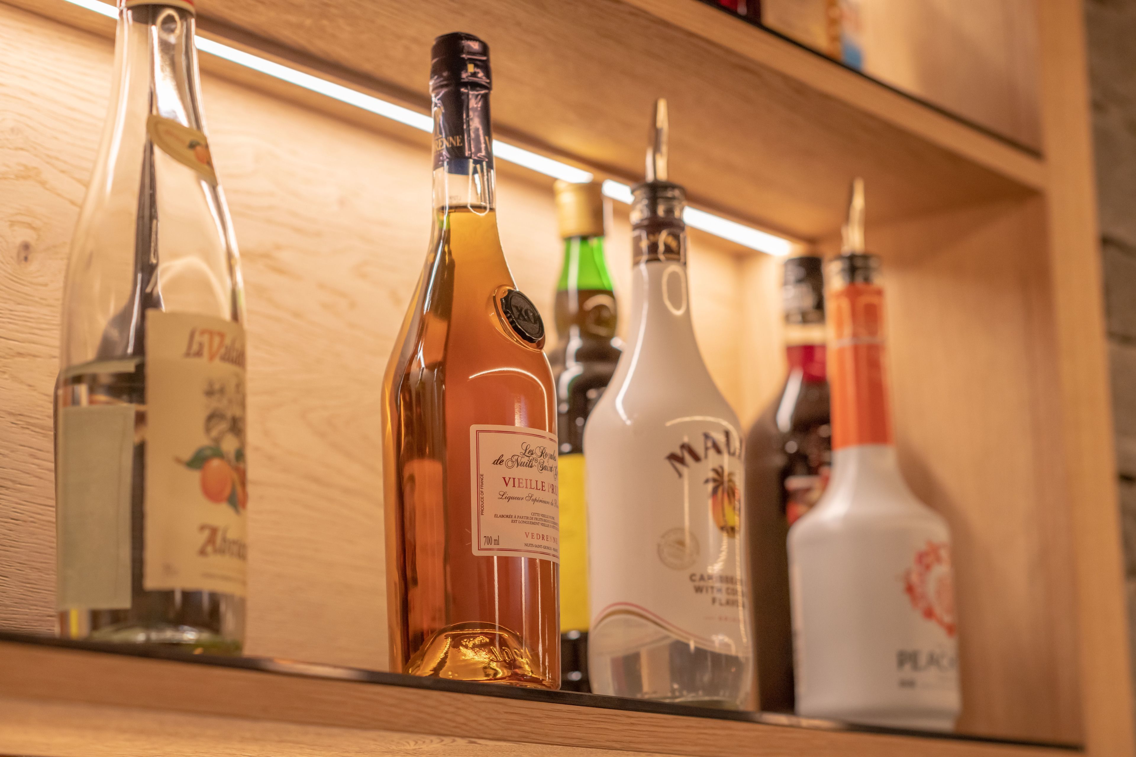 A shelf with various bottles of alcohol, including a bottle labeled "VIEILLE" and another labeled "MALI".