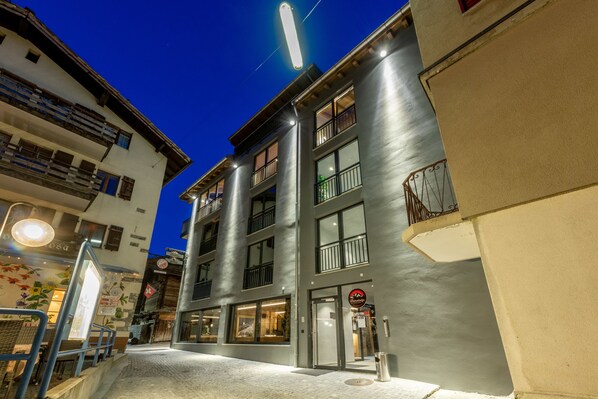 Un edificio de varios pisos con restaurante en la planta baja, ventanas amplias y una entrada visible.