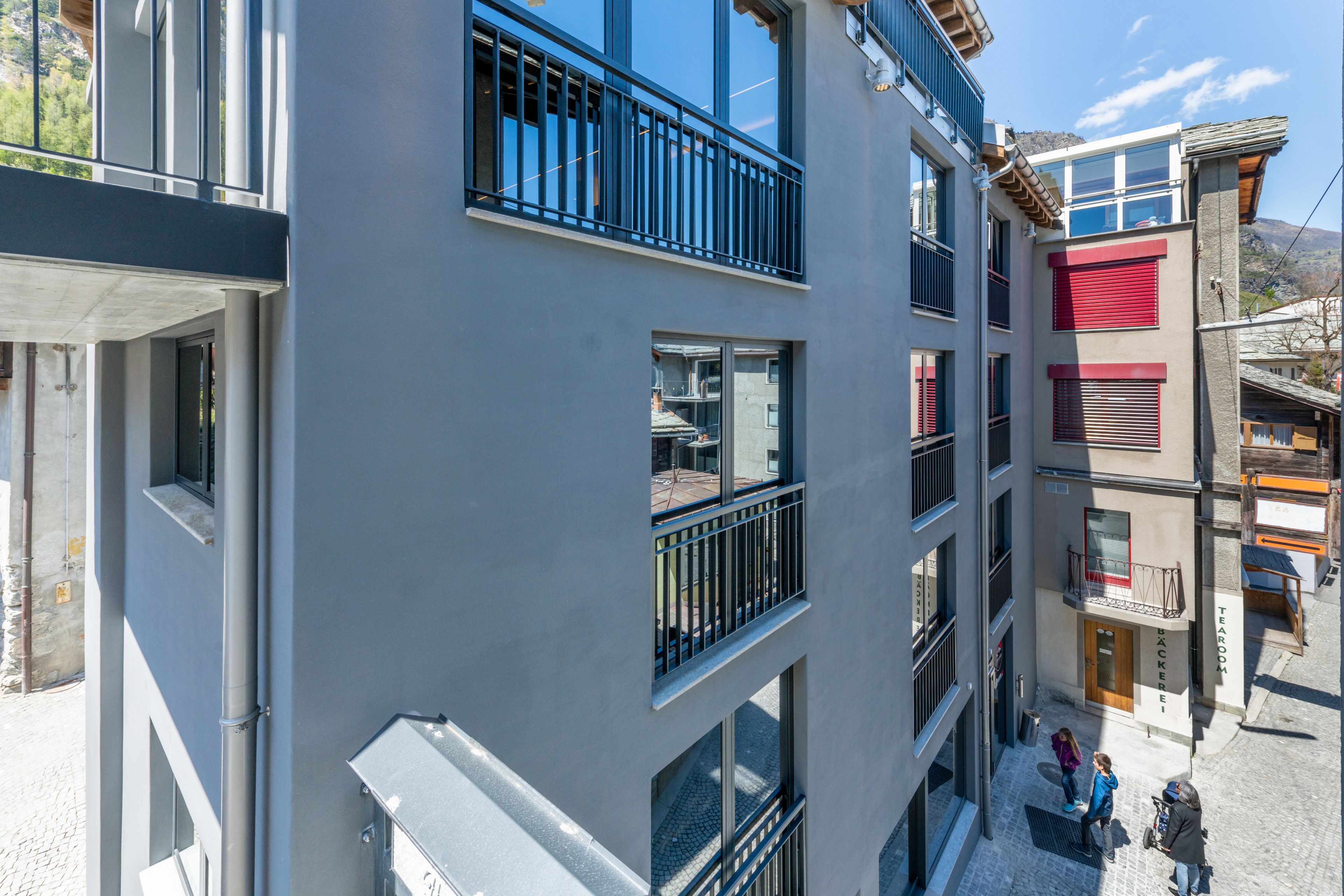 Un edificio de varios pisos con balcones, ventanas amplias y una entrada visible en la planta baja.