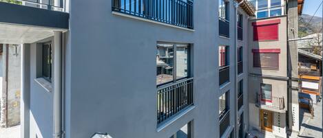 Un edificio de varios pisos con balcones, ventanas amplias y una entrada visible en la planta baja.