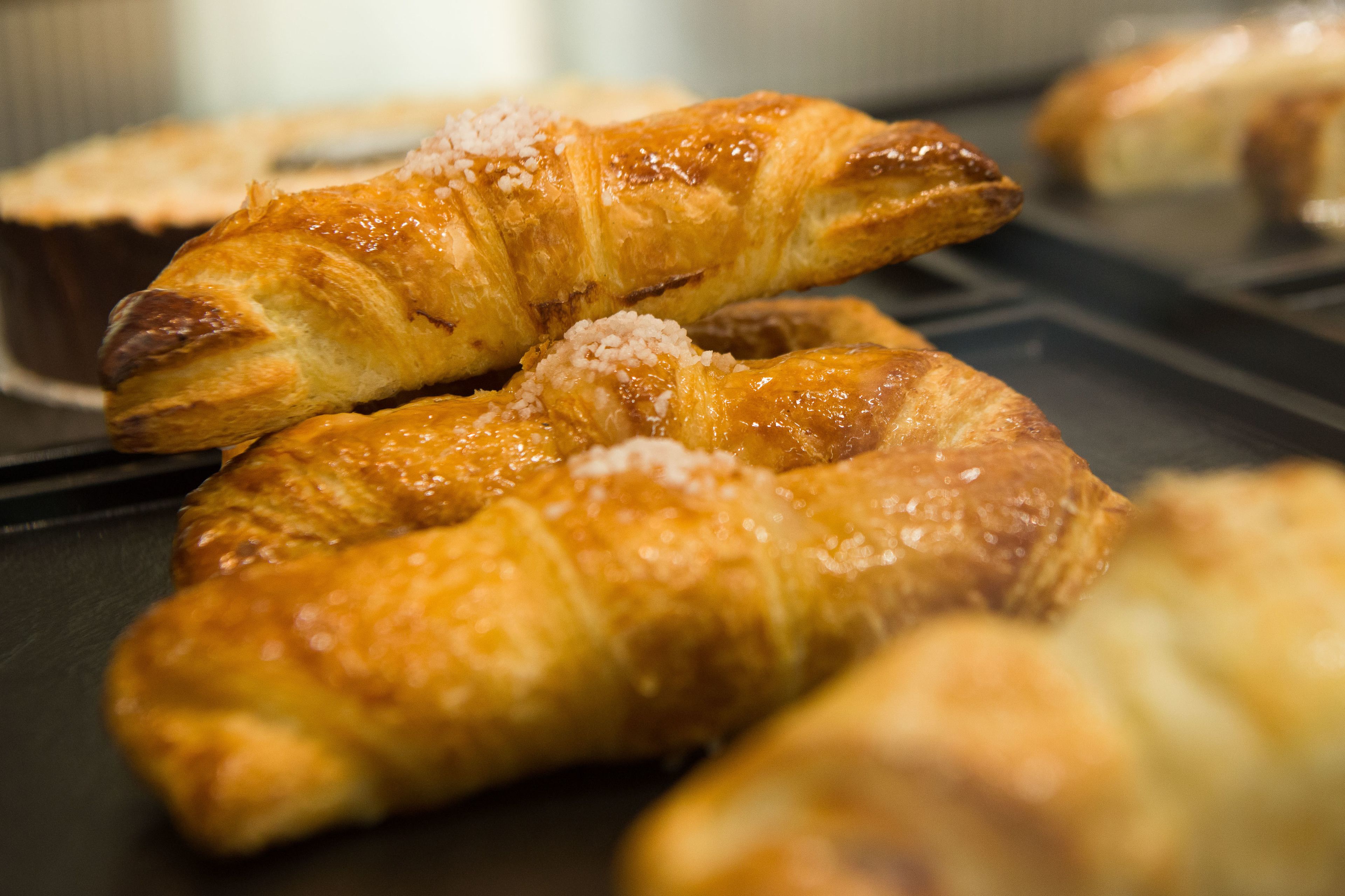 Primer plano de bollería dorada y crujiente, probablemente cruasanes, sobre una bandeja.