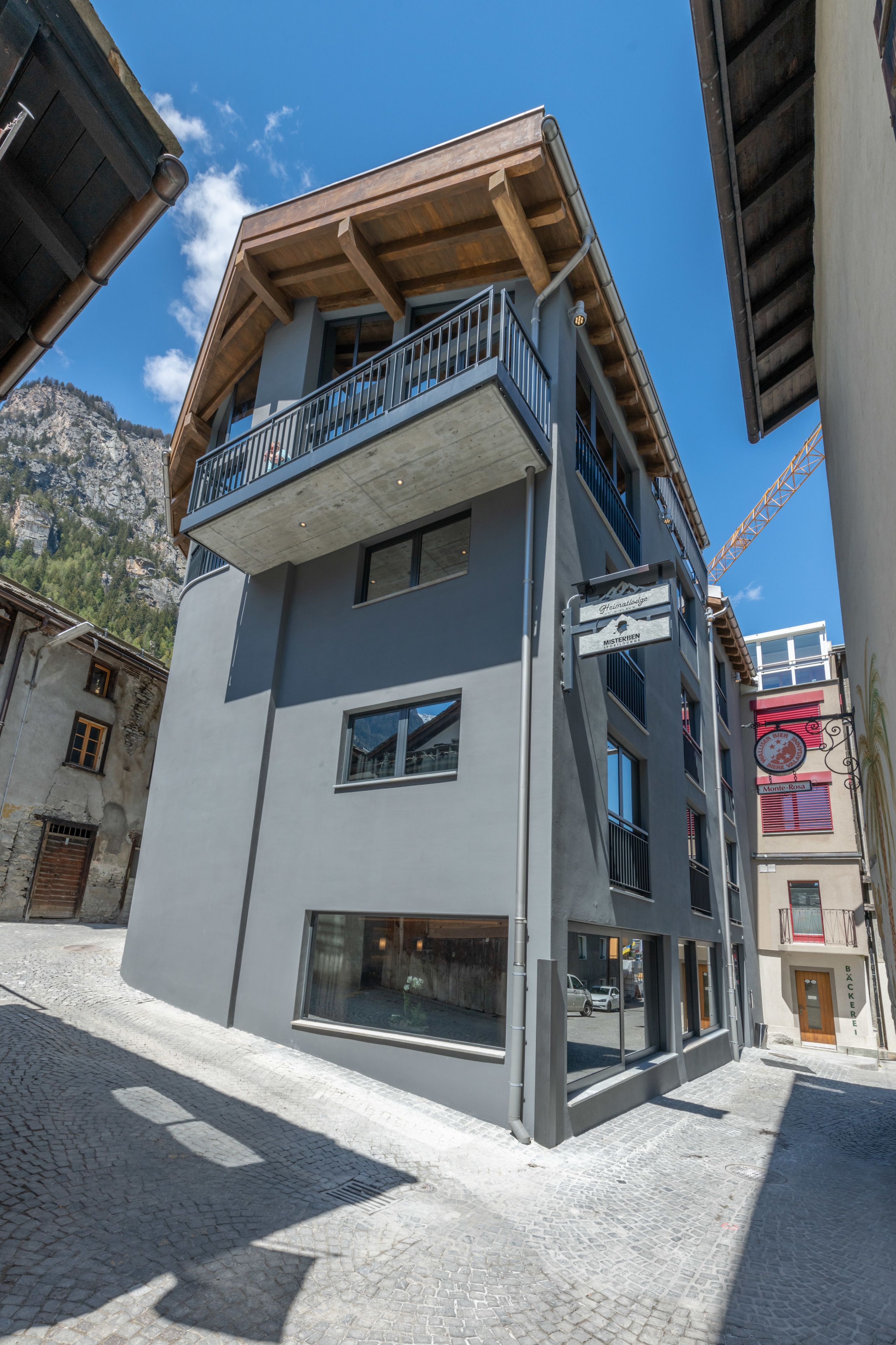 Un edificio de varios pisos con un balcón en el piso superior, ventanas amplias y un letrero que indica un restaurante.