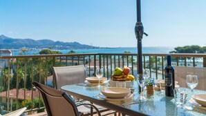 A table set for dining with a view of the ocean and mountains.