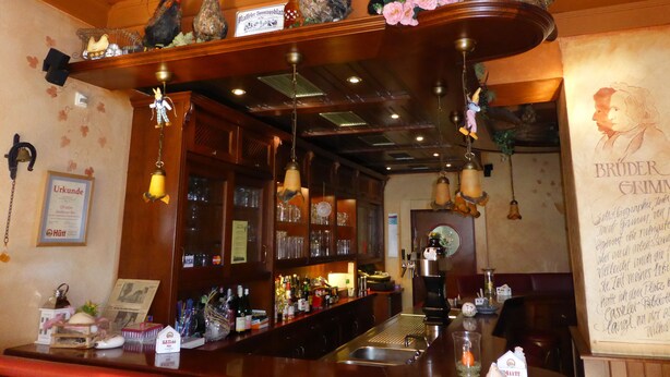 A bar area with wooden shelves, hanging lights, and a variety of bottles and glasses. - Zwehrener Hof (Kassel)