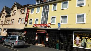 Ein Hotel mit gelber Fassade, einem roten Schild, das es als Hotel kennzeichnet, und einem gut sichtbaren Eingang.