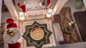 A dining area with a table set for two, surrounded by red chairs, a patterned rug, and decorative lanterns. - Riad Kech Soul Boutique & SPA (Marrakech)