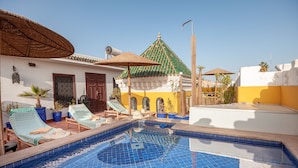 A swimming pool with lounge chairs and umbrellas, a building with a green roof, and a clear blue sky. - Riad Kech Soul Boutique & SPA (Marrakech)