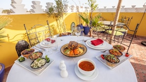 A table set for a meal with various dishes, including a large platter of food, bowls of salad, and a bowl of sauce. - Riad Kech Soul Boutique & SPA (Marrakech)