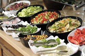 Un buffet proposant une variété de plats, notamment des salades, des légumes et des viandes.