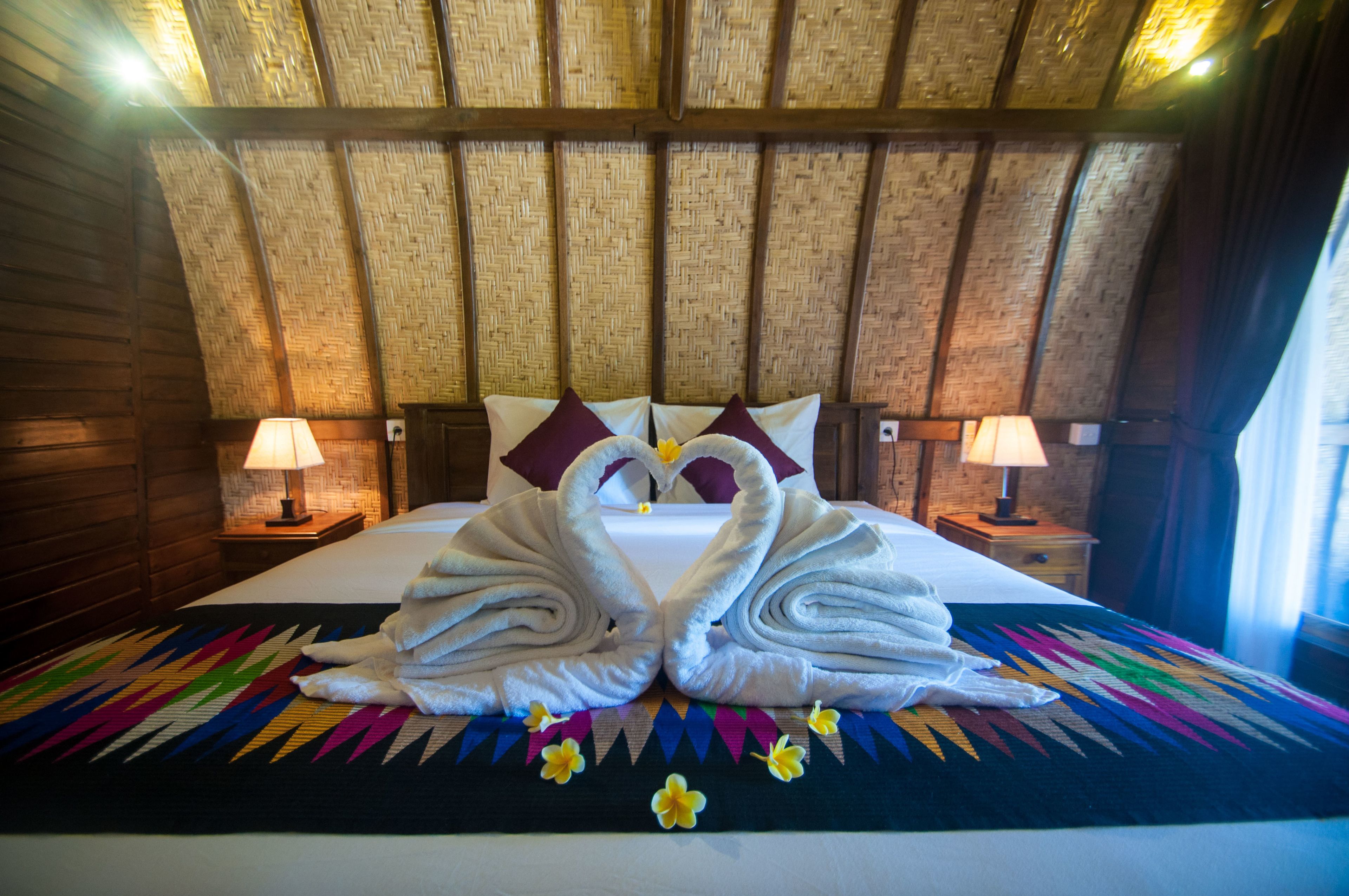 Habitación de hotel con una cama, dos mesitas de noche y un techo tejido.