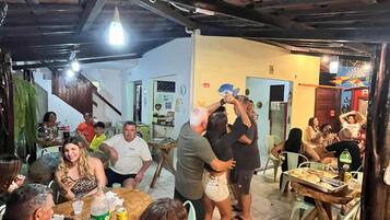 Un espacio interior concurrido, con gente reunida alrededor de mesas, algunas sentadas y otras de pie.