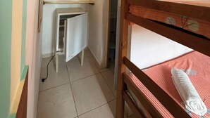 A narrow room with bunk beds, a small kitchenette, and an air conditioning unit. - Pousada Porto de Amigos (Ipojuca)