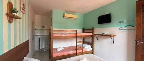 A bunk bed room with a single bed, a desk, and a television on the wall.