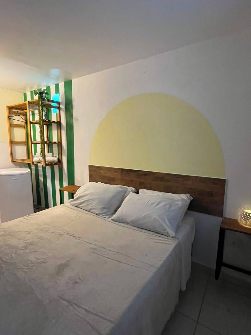 Une chambre à coucher comprenant un lit, une table de chevet, une étagère fixée au mur et un radiateur.