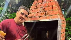A person grilling food outdoors next to a brick-built outdoor oven. - Pousada Porto de Amigos (Ipojuca)