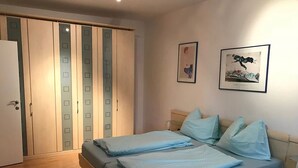 A bedroom with a bed, a nightstand, a wardrobe, and two framed pictures on the wall. - Appartementhaus Holiday & Villa Theresa (Kaprun)