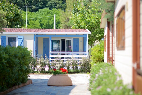 A house with a tiled roof, blue shutters, and a garden with a flower bed. - Camping Sun Beach (Torino di Sangro)