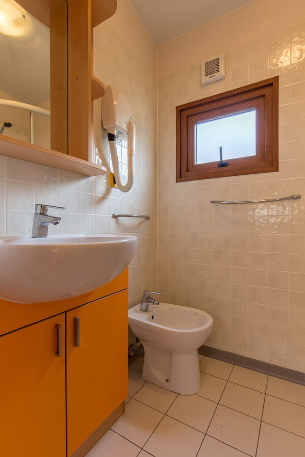 A bathroom with a white sink, a bidet, and a window. - Camping Sun Beach (Torino di Sangro)