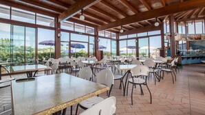 An indoor dining area with wooden beams, large windows, and outdoor umbrellas. - Camping Sun Beach (Torino di Sangro)