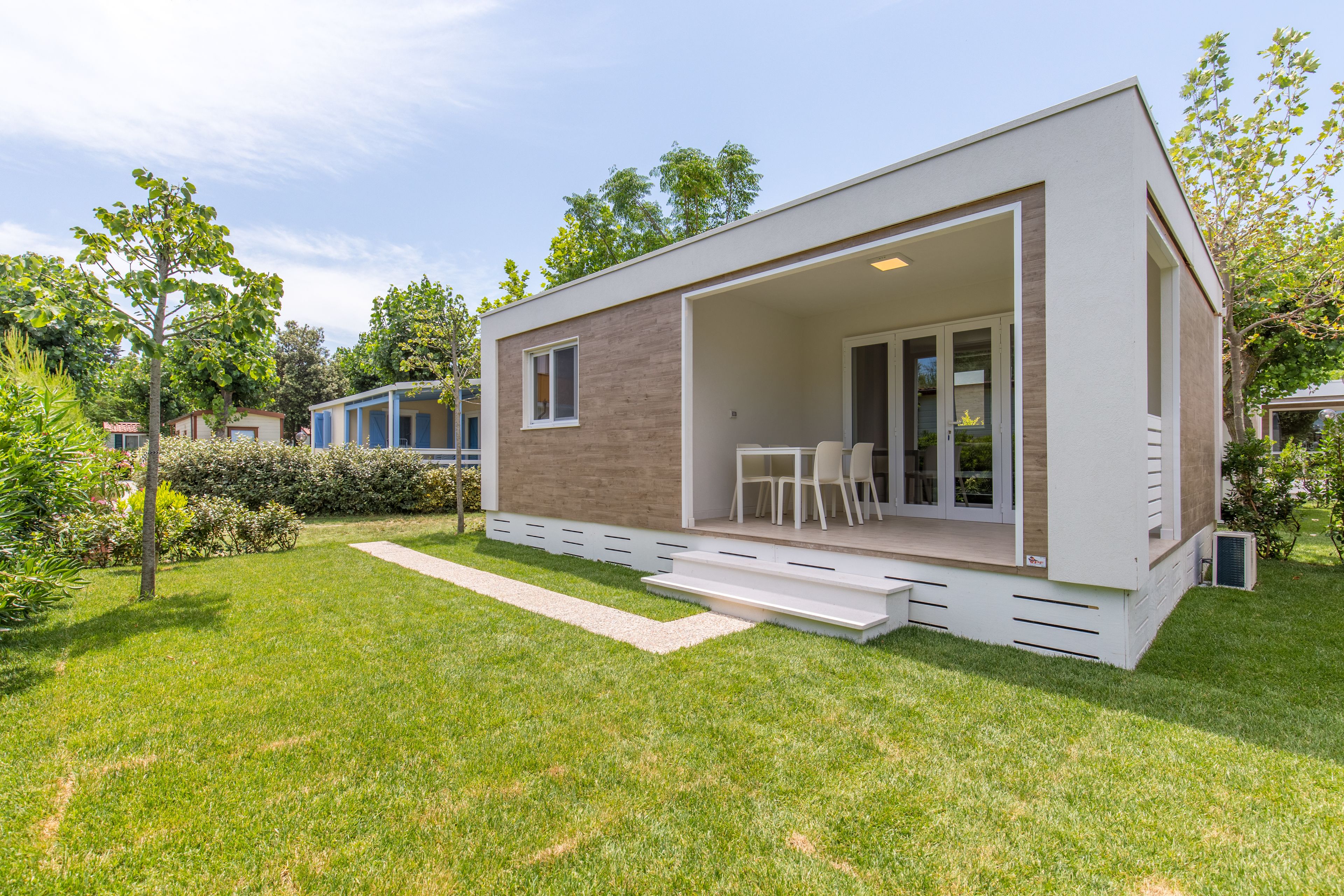 Une maison moderne de plain-pied dotée d’un patio, d’un coin repas et d’une grande porte-fenêtre coulissante.