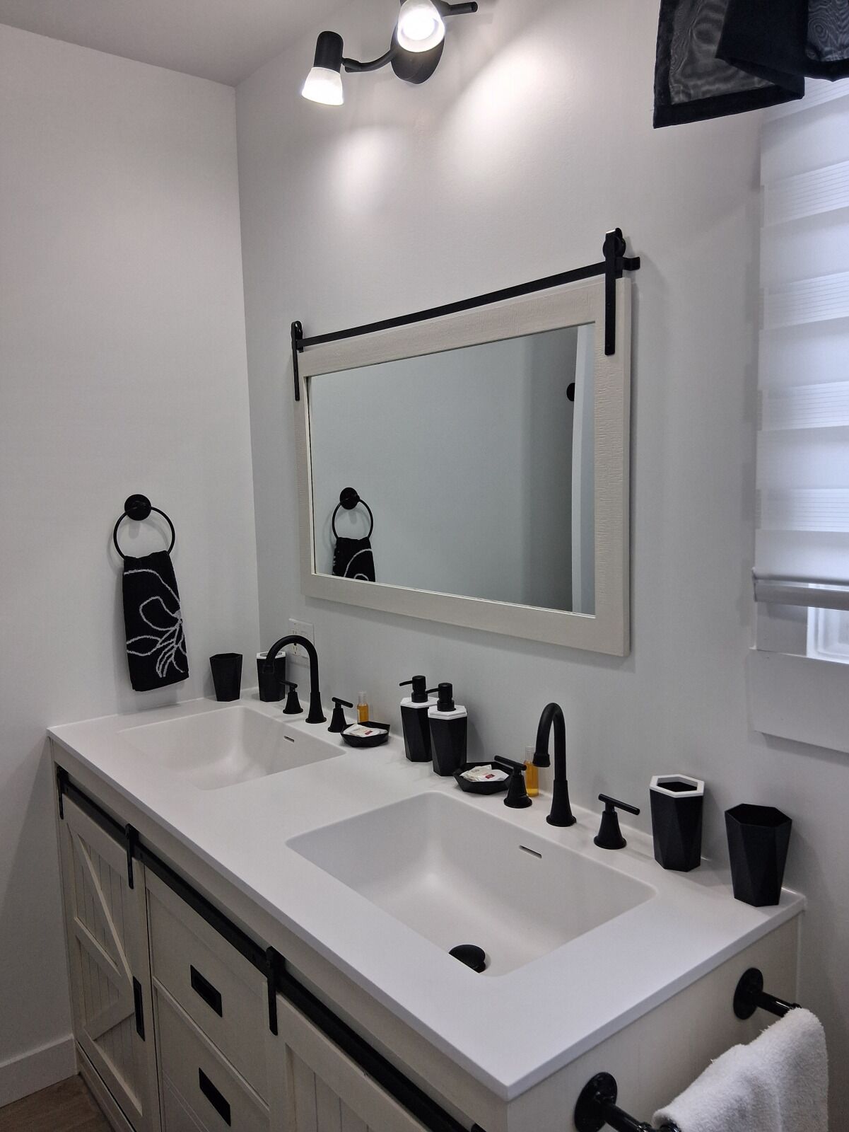 A bathroom with two sinks, a mirror, and a towel rack.