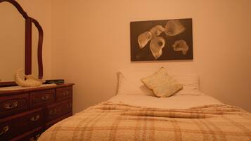 Une chambre à coucher comprenant un lit, une commode en bois, un miroir et une œuvre d’art accrochée au mur.