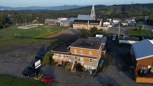 An aerial view of a residential area with a prominent church, a playground, and a parking lot. - Auberge St-Tite-des-Caps (Saint-Tite-des-Caps)