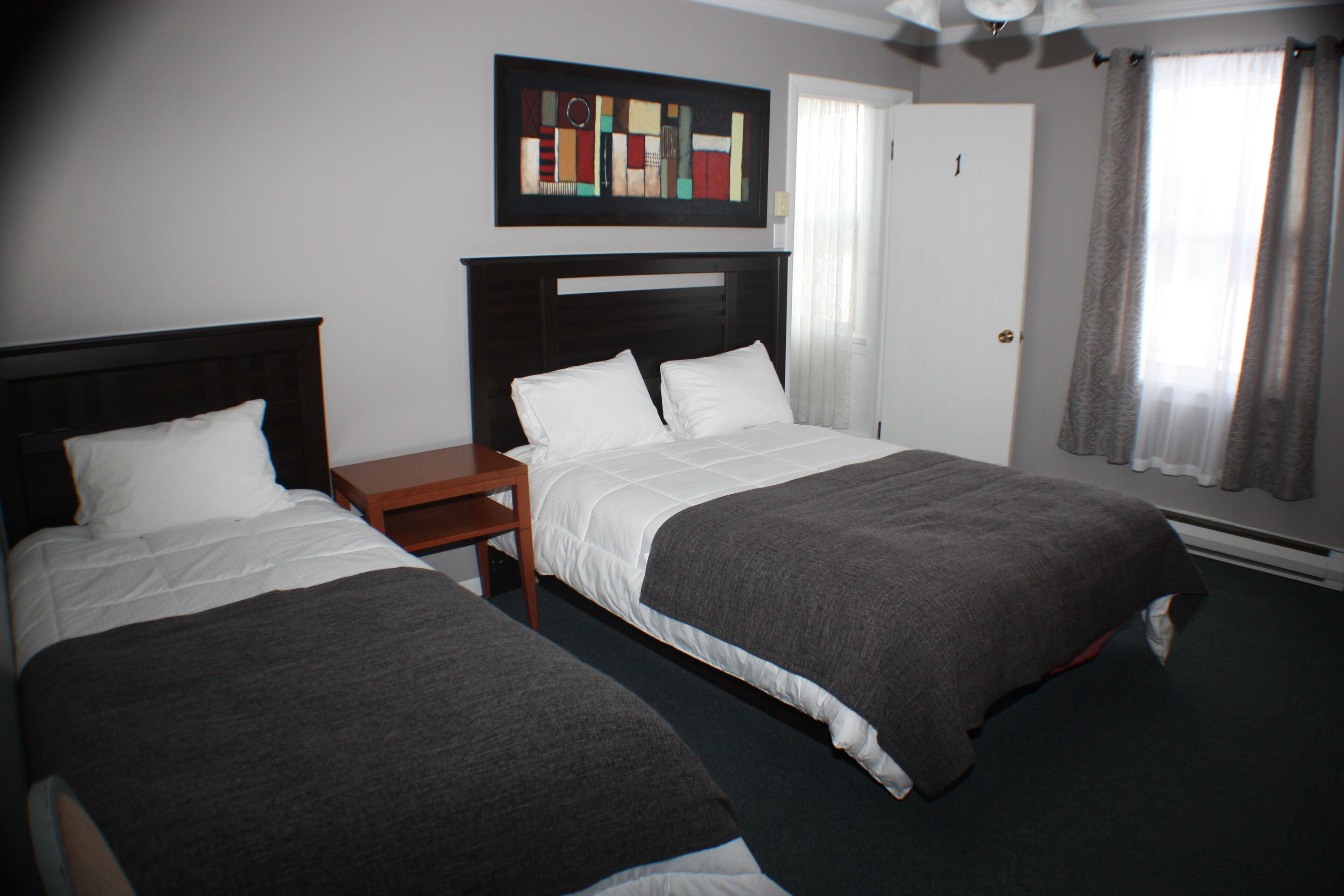 A hotel room with two beds, a nightstand, and a painting on the wall.