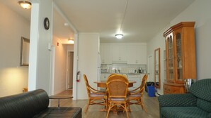 A living room with a black sofa, a green sofa, wicker chairs, and a dining table. - Auberge St-Tite-des-Caps (Saint-Tite-des-Caps)