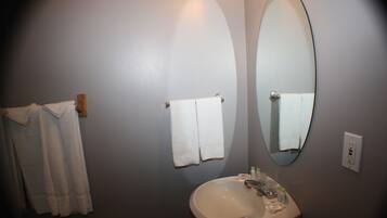 A bathroom with a sink, two towels hanging on hooks, and a mirror.