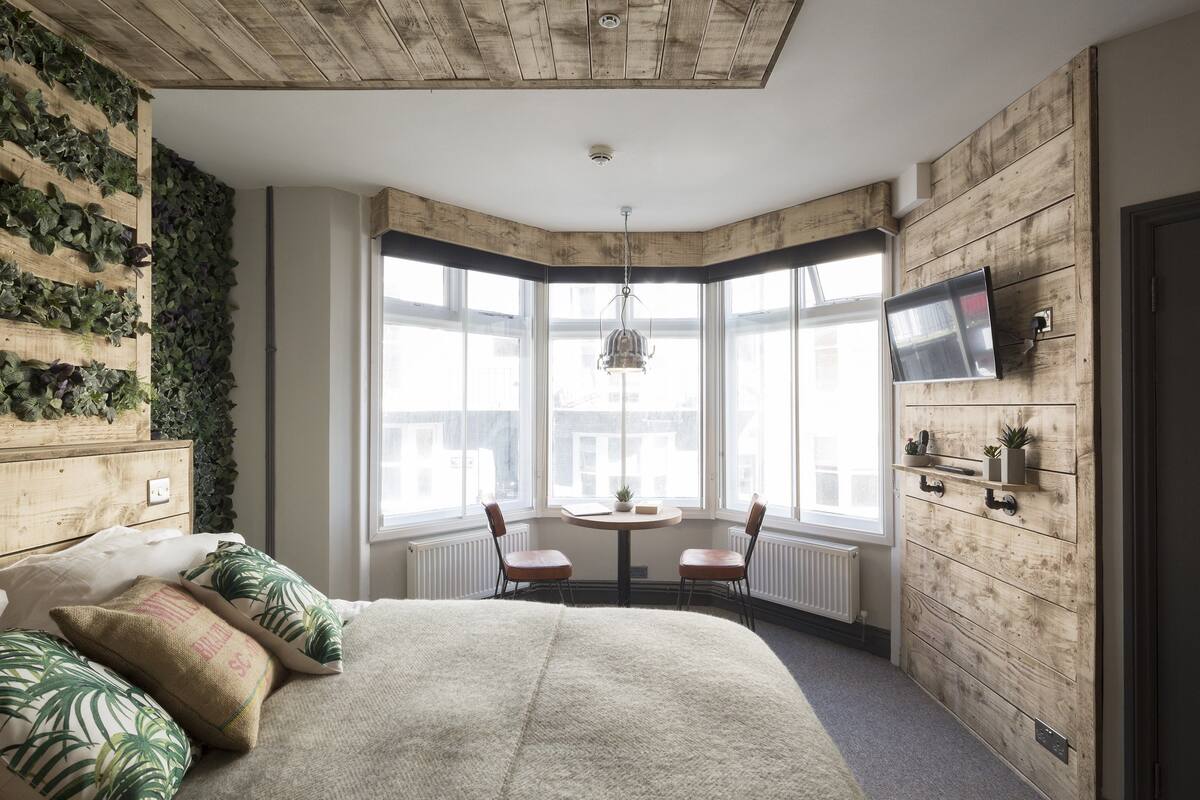 A bedroom with a large bed, a wooden wall, a TV, and a view of the city.