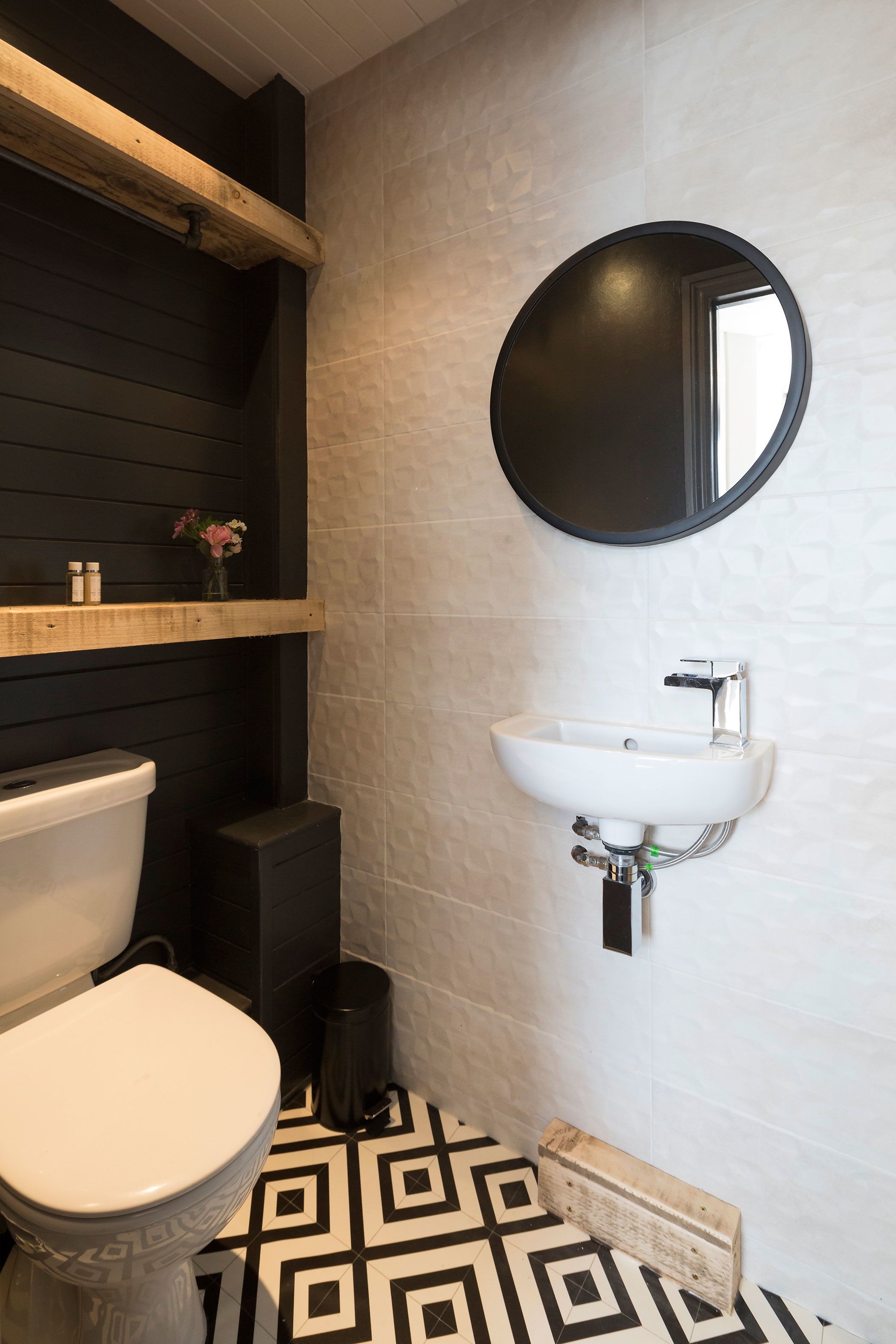 A bathroom with a toilet, sink, and mirror.