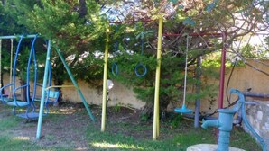 A playground with swings, a slide, and a climbing structure. - Villa Eva Agios Nikolaos (Sithonia)
